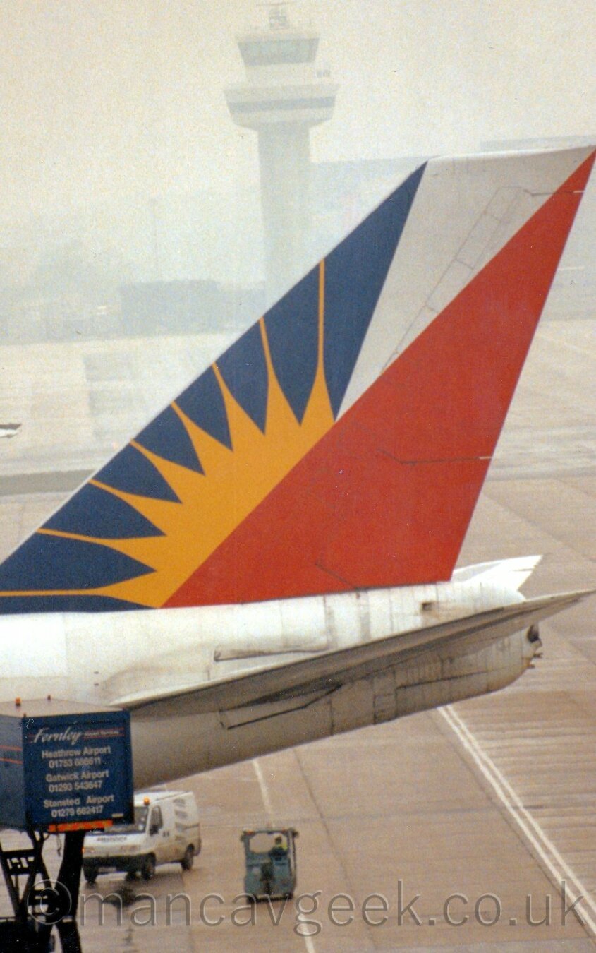 Close up of a white jet airliner tail, with blue and red triangles and a rising sun symbol..