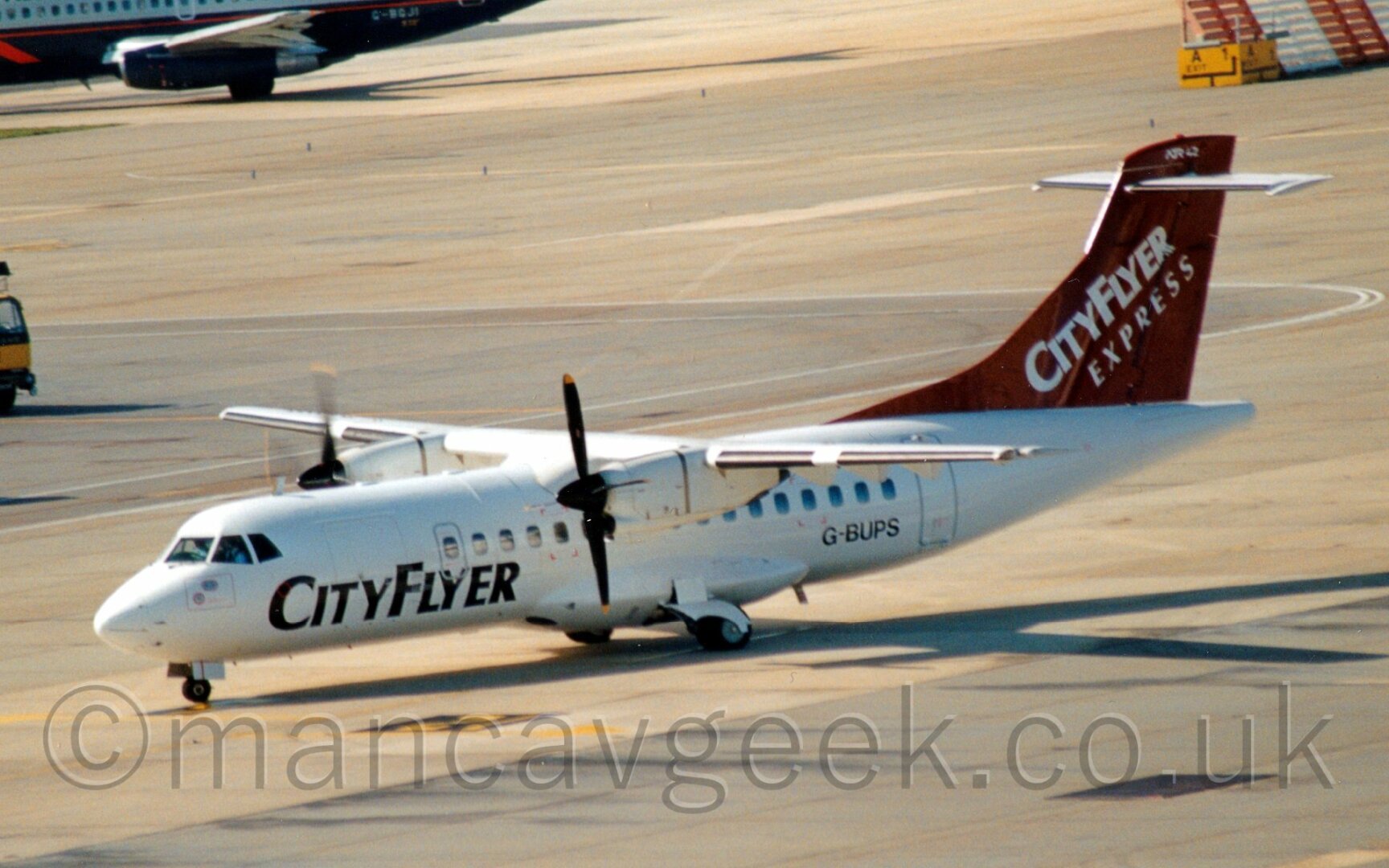 White propellor airliner with a mauve tail with"CityFler Express" titlesat an airport.