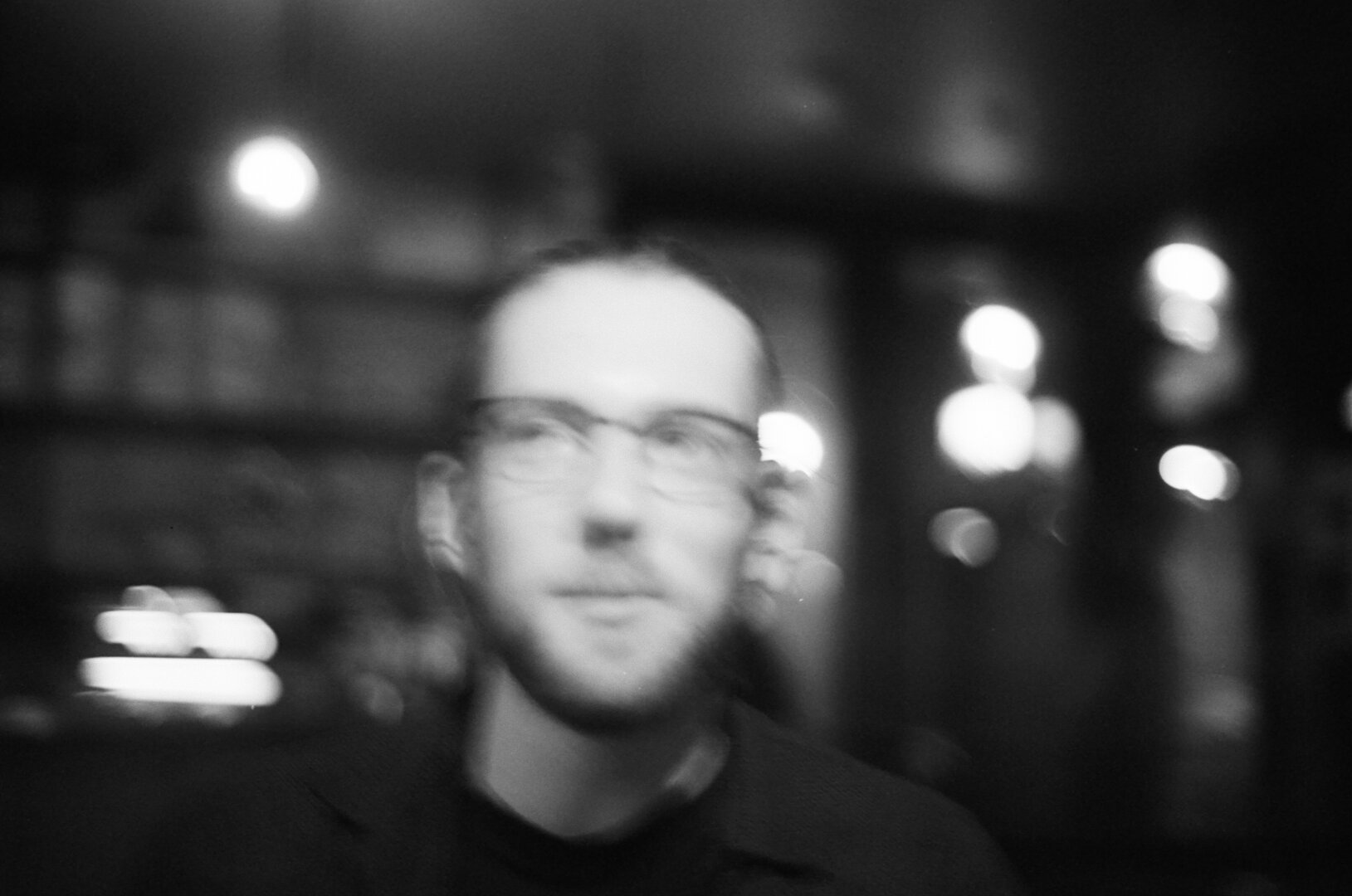 A blurred, black and white photo of a person, looking to one side but facing the camera