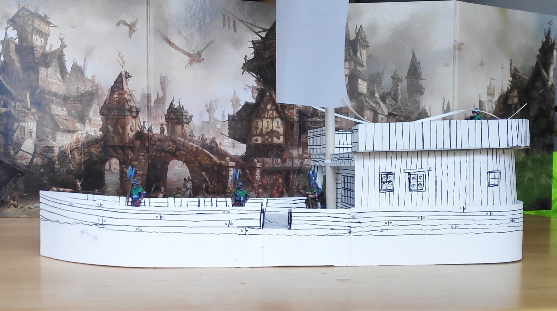 Maquette en papier cartonné d'un chaland (le bateau, pas le promeneur) fait maison. Une cabine occupe le tiers arrière, un mat avec une voile carrée est planté juste avant la cabine. Cinq figurine de soldats à morion et hallebarde sont posées sur le pont, pour donner l'échelle