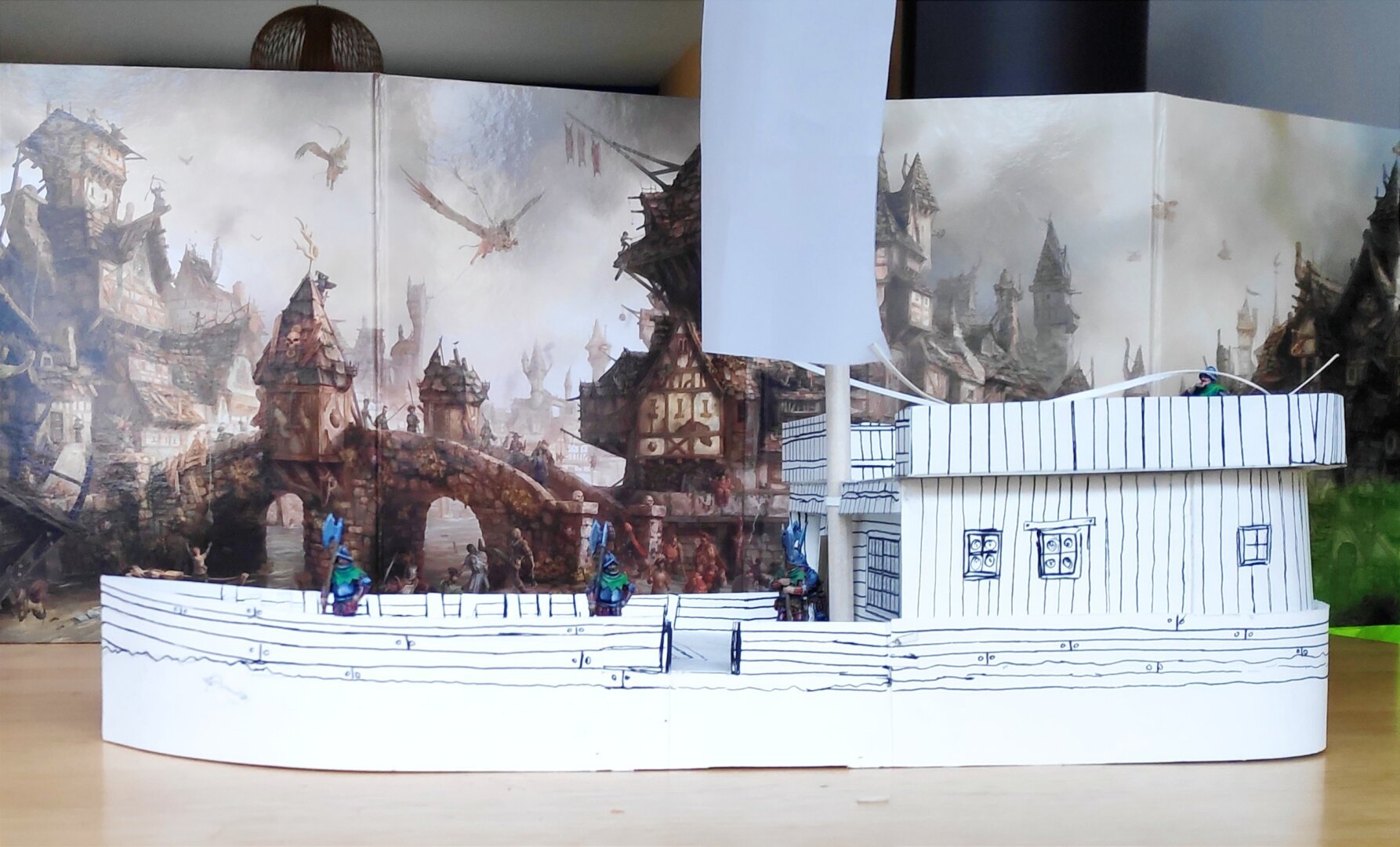 Maquette en papier cartonné d'un chaland (le bateau, pas le promeneur) fait maison. Une cabine occupe le tiers arrière, un mat avec une voile carrée est planté juste avant la cabine. Cinq figurine de soldats à morion et hallebarde sont posées sur le pont, pour donner l'échelle.